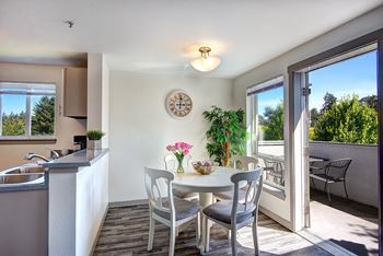 a dining room with a white table and chairs and a kitchen with a sink